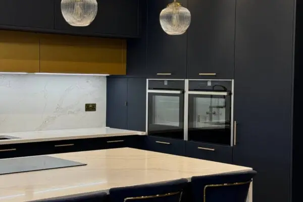 Waterfall kitchen island with quartz worktops and integrated NEFF appliances in a navy blue kitchen