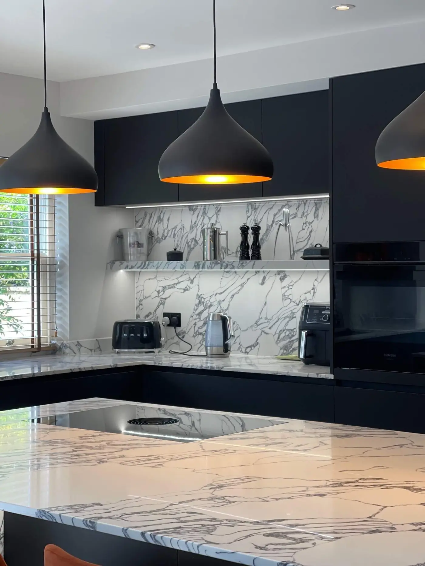 Dark grey kitchen with contrasting white veined stone worktops and pendant lighting